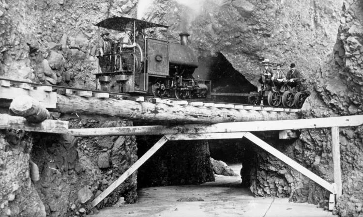 Steam locomotive on tramway by cliffs, north of Whatipu.