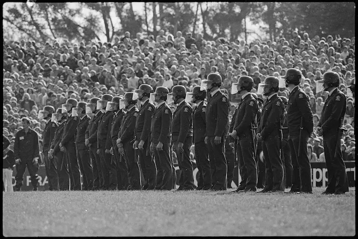 Policemen in riot helmets standing on Rugby Park, Hamilton, during the Springbok rugby tour - Photograph taken by Ian Mackley