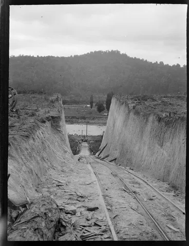 Image: A cutting through a steep embankment with a rail track for a cable pulled railway carriage to move large logs from the river to the Kakahi Sawmill, Kakahi Settlement, Manawatu-Whanganui Region