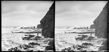 Image: Stormy coastal scene, featuring kelp and cliffs, and including an unidentified boy standing on a rock, Black Head, Dunedin, Otago Region