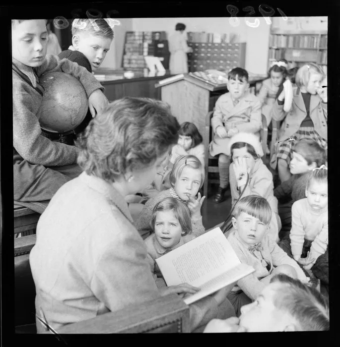 Unidentified woman reading a book to children at story time at the Wellington Public Library