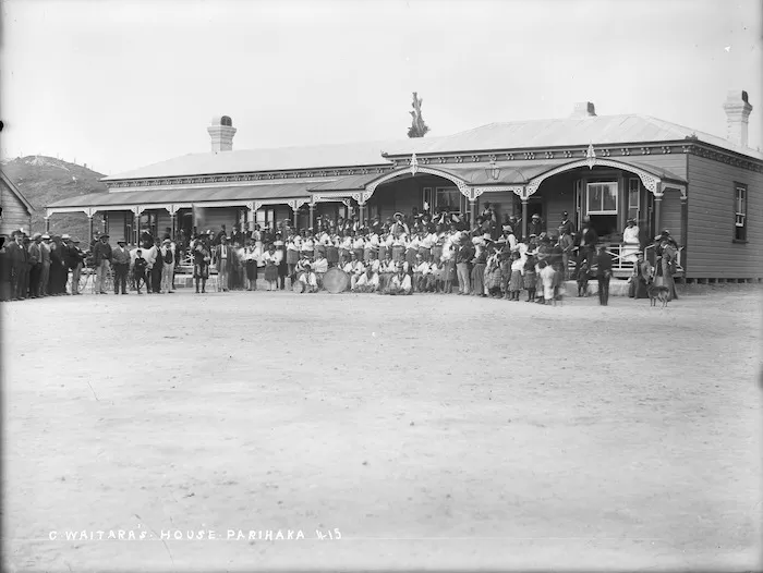 Band of flute and drum players, and others, outside the house of Charles Waitara, at Parihaka