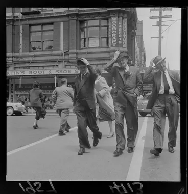 Image: Men holding their hats in a Wellington wind