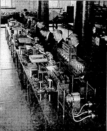 Image: The Murray Multiplex Printing Set enables four rne^sages, at the rate of 43^ords per minute, to be sent in each direction over a single Hrie—a total of 344 wordi per minute. A tape is perforated by working the keyboard; and four of theW tapes are worked simultaneously into the transmitter. At the receiyihg station the signal impulses of the four messages are sorted out and the text is automatically typed put. The actual typing of a letter by the receiver takes place about a twentieth of a second after the sender has depressed the key. (Evening Post, 08 February 1935)