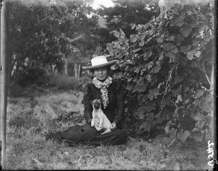 Woman with a dog seated on the grass, 1910s
