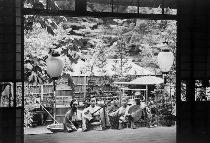 Japanese women in a courtyard in Japan, two holding stringed instruments