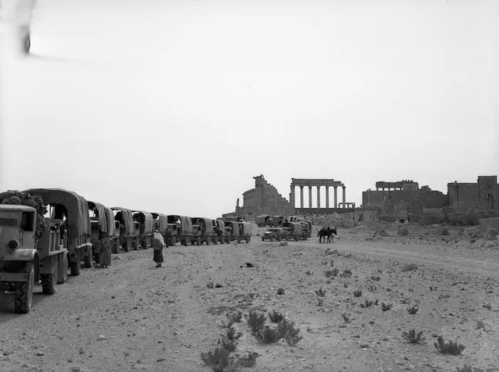 A convoy of New Zealand army trucks pass by the ruins of Palmyra, Syria