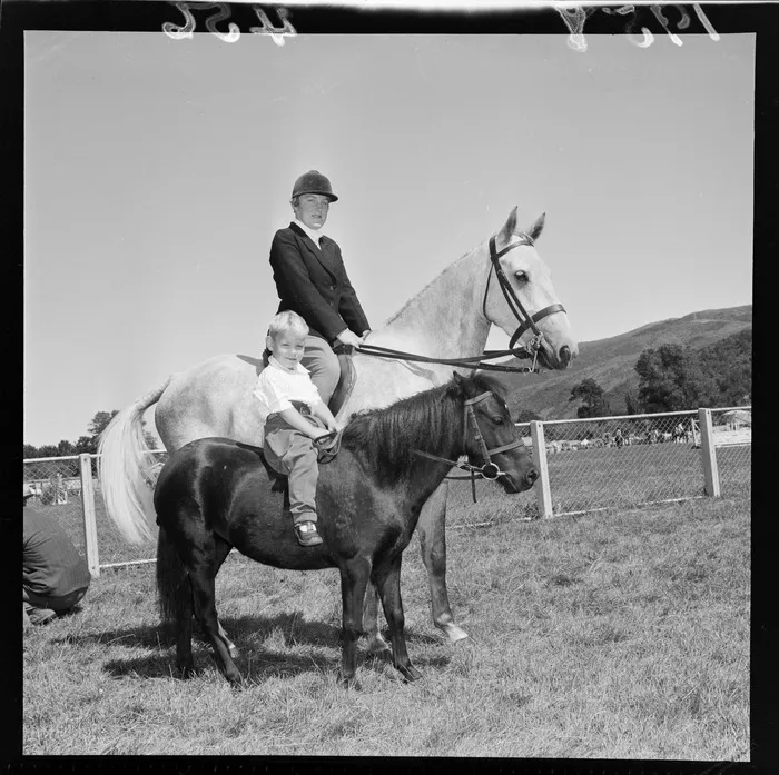 Unidentified woman rider and unidentified child on a miniature horse, during the 1958 A&P (agricultural and pastoral) show at Trentham, Upper Hutt