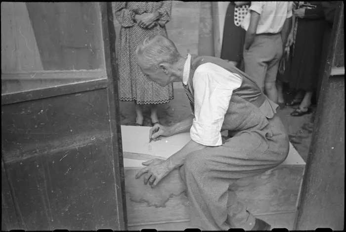 Italian civilian inscribing the name of German sniper victim on a coffin in Florence, Italy, World War II - Photograph taken by George Kaye
