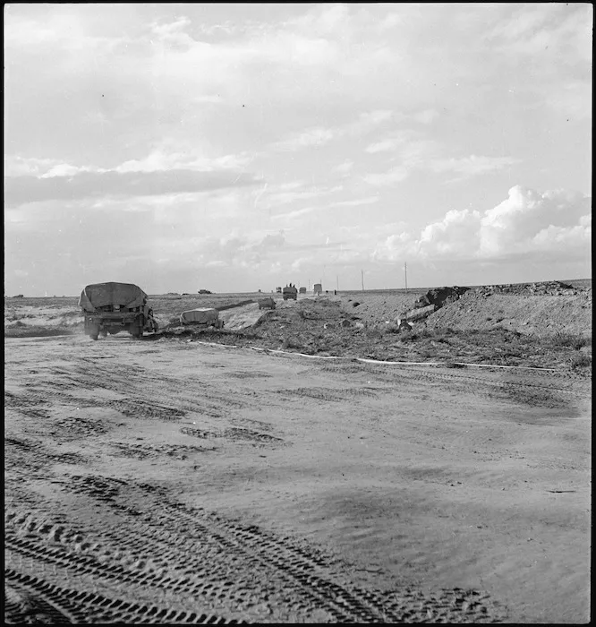 World War II transport bypassing demolished bridge travels past taped track through minefield near Sirte, Libya