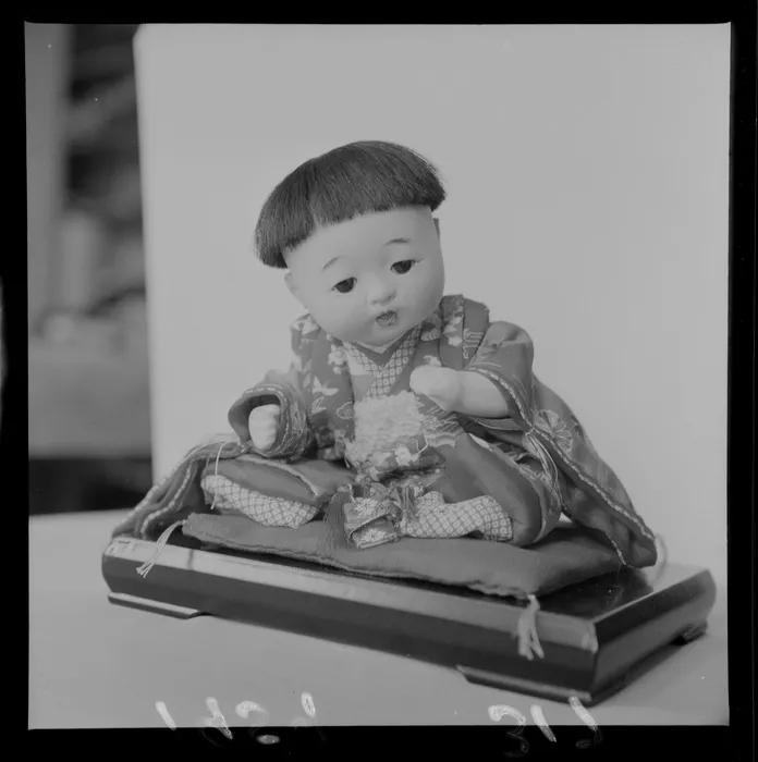 Small Japanese doll sitting on a cushion