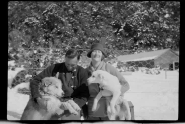 Image: Unidentified man and woman, sitting on kennel with two huskies, Mount Cook area