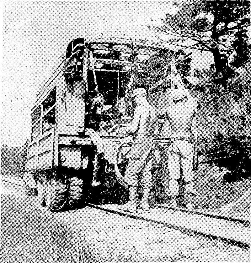 Marines of a 6th Division signal company repairing telephone lines on Okinawa, with their heavy truck straddling the narrow-gauge Japanese railway. (Evening Post, 23 June 1945)