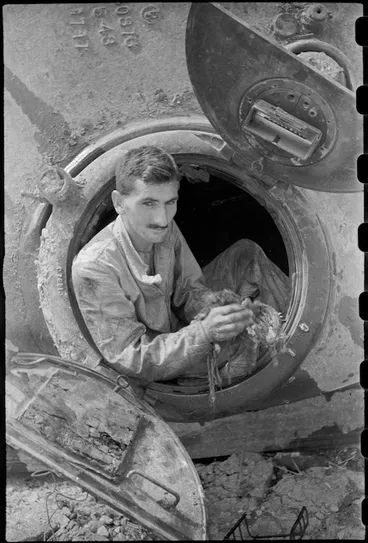 Image: M W J McNicol finishes checking over interior of a World War II NZ Sherman tank near Florence, Italy - Photograph taken by George Kaye