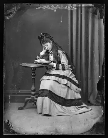 Image: Young woman [from Wargan family] looking at photograph album