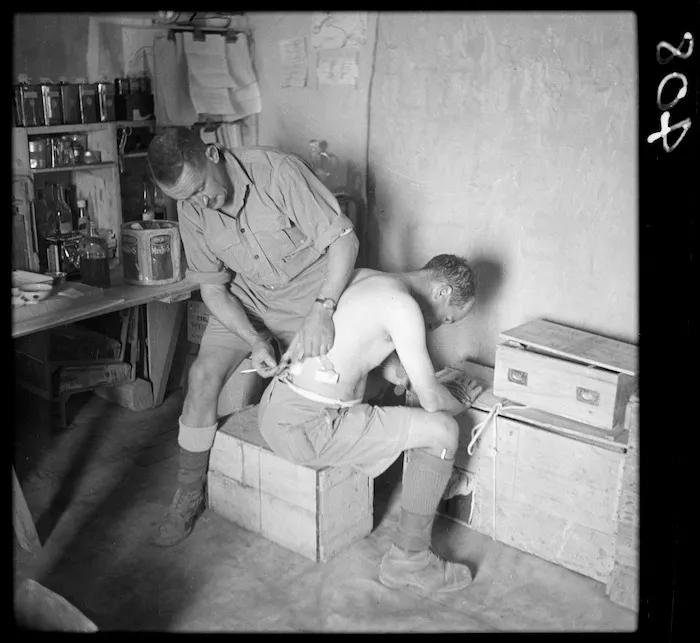 New Zealand medical officer attending a patient at a regimental aid post in the Western Desert, North Africa, during World War 2