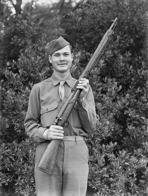 [U.S. military serviceman poses for a portrait holding rifle]