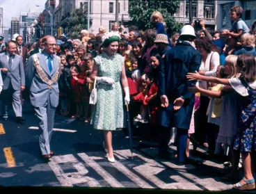 Fletcher Construction Co Ltd: 1977 Manukau Shopping Centre, Auckland - Queen Elizabeth II visit - Crowd scenes inside mall - Queen standing by window Image: Fletcher Construction Co Ltd: 1977 Manukau Shopping Centre, Auckland - Queen Elizabeth II visit - Crowd scenes inside mall - Queen standing by window