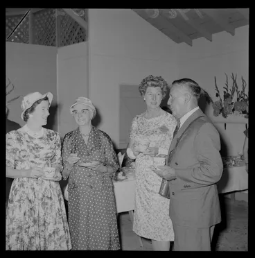Image: Personalities at the Tauherenikau Racecourse with three unidentified women and a man indoors dressed for the occasion, Wairarapa District