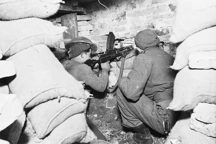 Kaye, George 1914- : Soldiers of 23rd NZ Battalion, firing a Bren machine gun from a house in the Faenza area, Italy