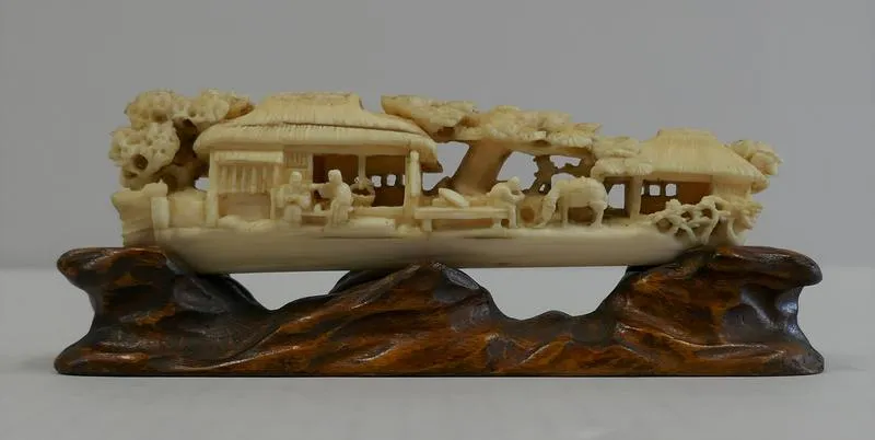 Warabuki kaya to taija (chaya fukei) [straw thatched house and a large tree]; Ivory carved fantastic boat with trees, houses, people and a horse and wooden base.