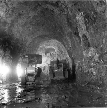 Image: Fletcher Construction Co Ltd, Civil Engineering Division - Christchurch-Lyttelton Road Tunnel: 1962 during construction - mucking with CAT977 with bucket - ventilation drive showing at top of tunnel