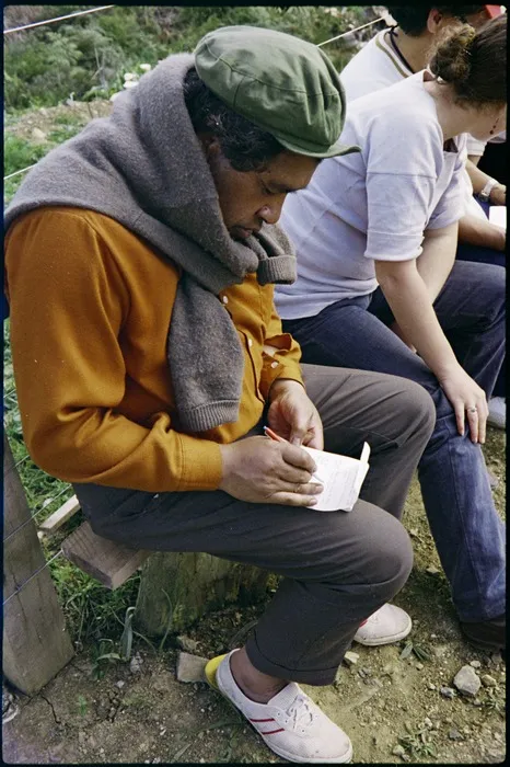 Poet Hone Tuwhare writing in his notepad during a stop on the Māori Land March