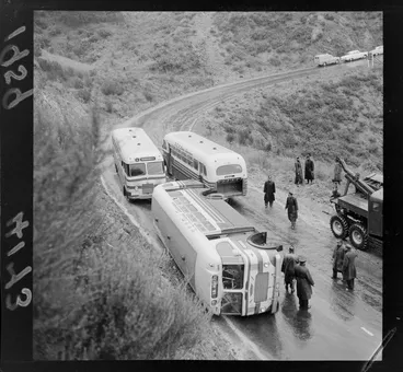Image: NZR Road Services bus overturned on way down Wainuiomata Hill in wet conditions with police and tow truck in attendance, Lower Hutt, Wellington Region