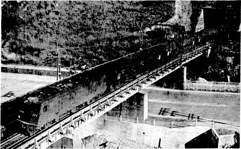 Evening Post" Photo. An electric locomotive pulling a north-bound train over a bridge in Ngahauranga Gorge yesterday afternoon. (Evening Post, 14 September 1940)
