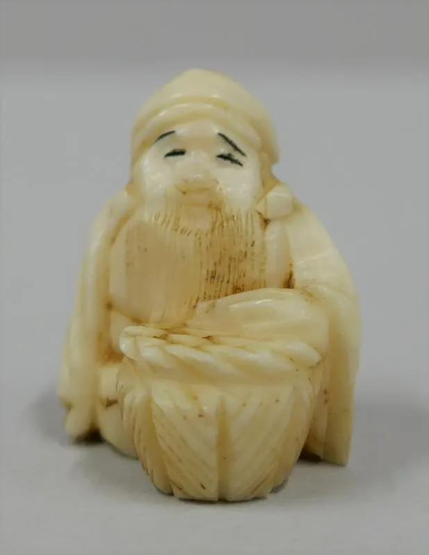Netsuke: Daikoku [Daikoku God]; Netsuke in the form of a man, seated, hatted, bearded with a drum.