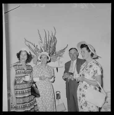 Image: Personalities at the Tauherenikau Racecourse with three unidentified women and a man indoors dressed for the occasion, Wairarapa District