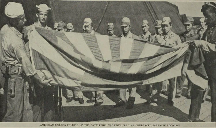 American sailors folding up the battleship Nagato's flag as grim-faced Japanese look on