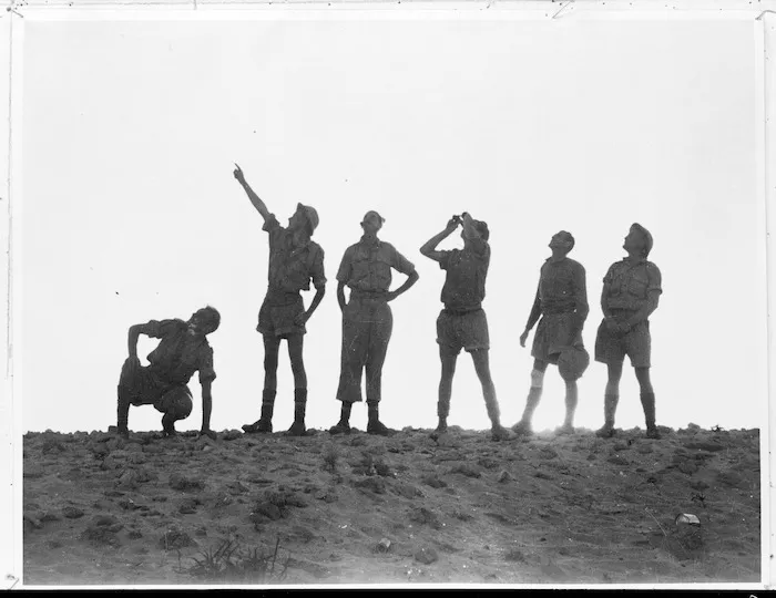 Group of New Zealand soldiers watching aircraft at sunset, Western Desert, during World War II