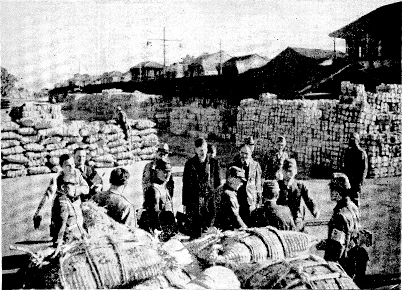 Thousands of packages of provisions stacked on the wharves at Wuchang after being unloaded from Japanese transports. Foreign cor- respondents, escorted by Japanese officers, are seen inspecting the supplies* (Evening Post, 17 February 1939)