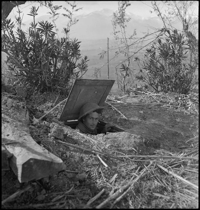 D G Bond looks out from entrance to duggout outside German HQ near Castelfrentano, Italy - Photograph taken by George Kaye