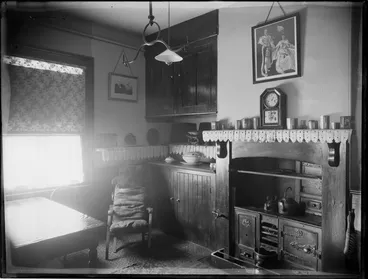 Image: Kitchen in unidentified house in Christchurch. The "lace" decorations on the mantle are made of newspaper. Above the clock is a portrait of King Edward VII and Queen Alexandra