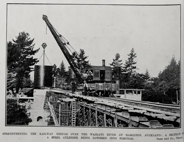 Image: STRENGTHENING THE RAILWAY BRIDGE OVER THE WAIKATO RIVER AT HAMILTON, AUCKLAND: A SECTION OF A STEEL CYLINDERS BEING LOWERED INTO POSITION