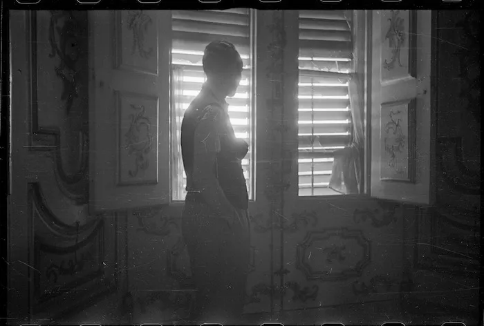 Person behind the shutters of the Pitti Palace, Florence, Italy, during World War II, looking across to where German Spandau nests and snipers are active - Photograph taken George Kaye