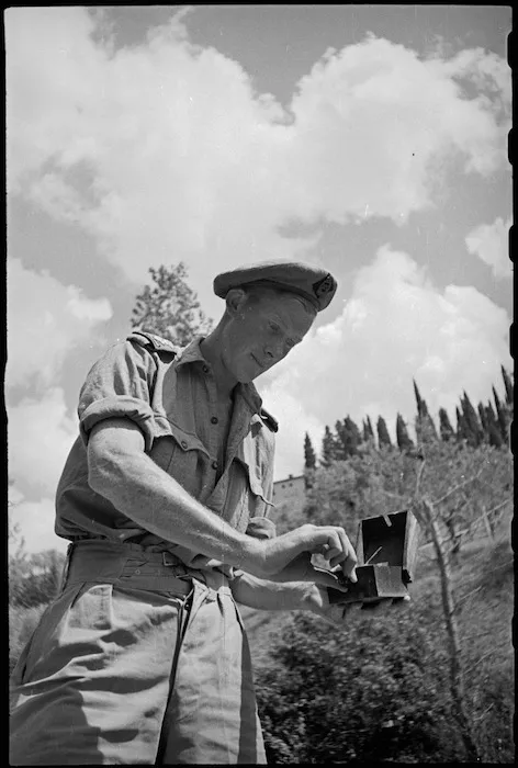 Lieutenant B C Moss examines a German Shoe Mine lifted in forward areas near Florence, Italy, World War II - Photograph taken by George Kaye