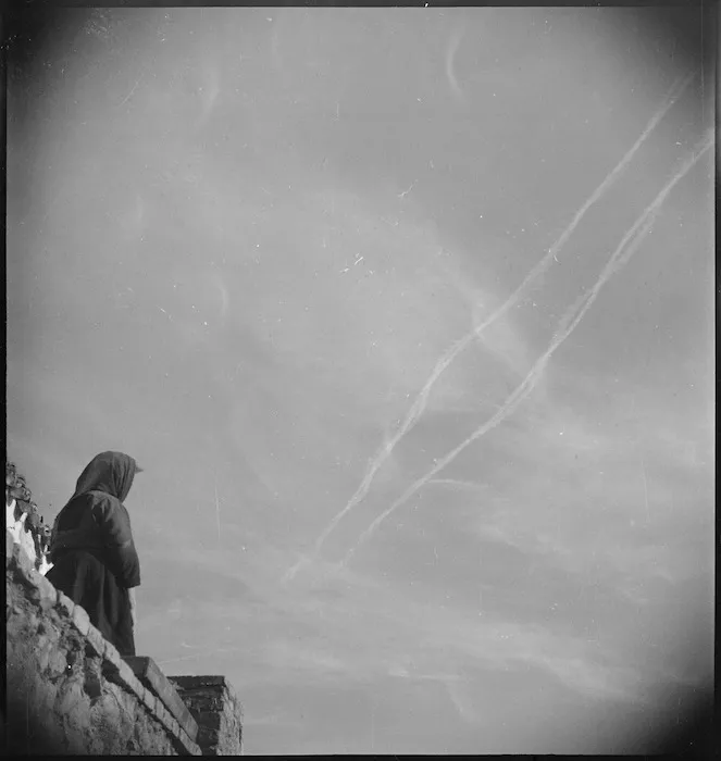 An Italian peasant woman watches the vapour trails from Allied aircraft over the Sangro River Front, World War II - Photograph taken by George Kaye