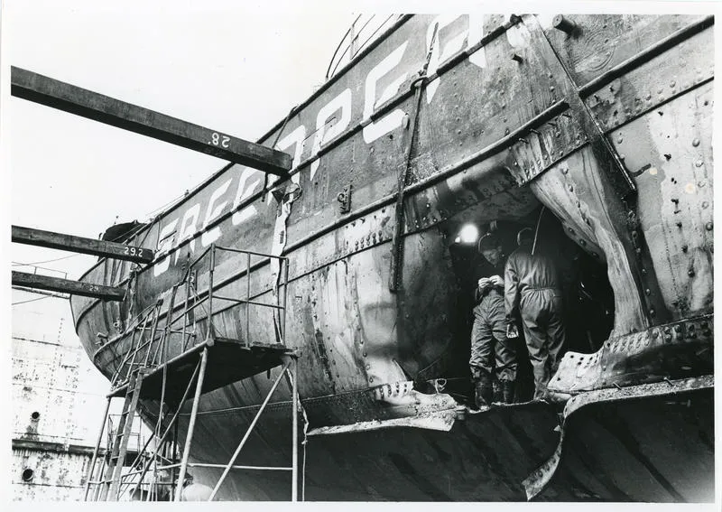 Photograph: Two detectives stand in hole in RAINBOW WARRIOR (1955) following bombing, 1985