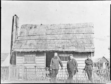 Image: Three men standing in front of a cottage, Ngāruawāhia, 1864