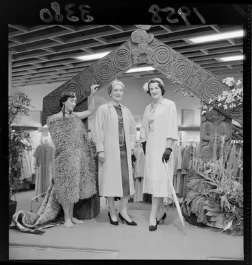 Image: Fashion display with fake Maori backdrop at Kirkcaldie & Stains department store, Wellington, featuring models in coats and a woman in traditional Maori dress