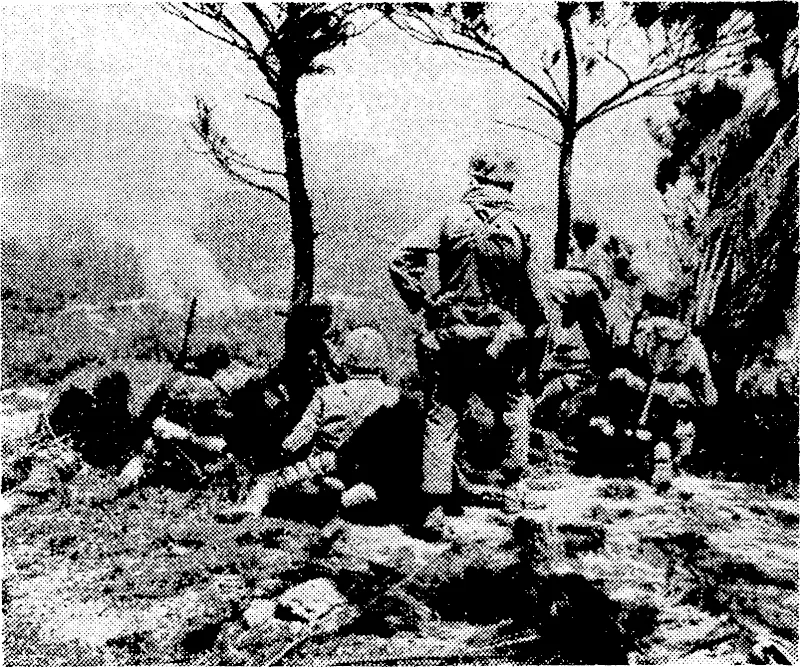 United States marines pause at the edge of an Okinawa mountain lop, waiting for artillery to blast a Japanese position that has been holding them up. (Evening Post, 17 May 1945)