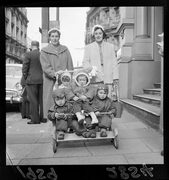 Two women, with four small children in a pushchair, all unidentified, on an unidentified street, probably Wellington region
