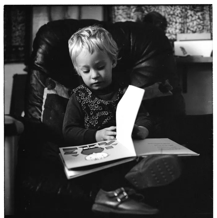 Child seated in a chair reading a book; scenes in a schoolroom; and, two Māori women and a child in the grounds of a school