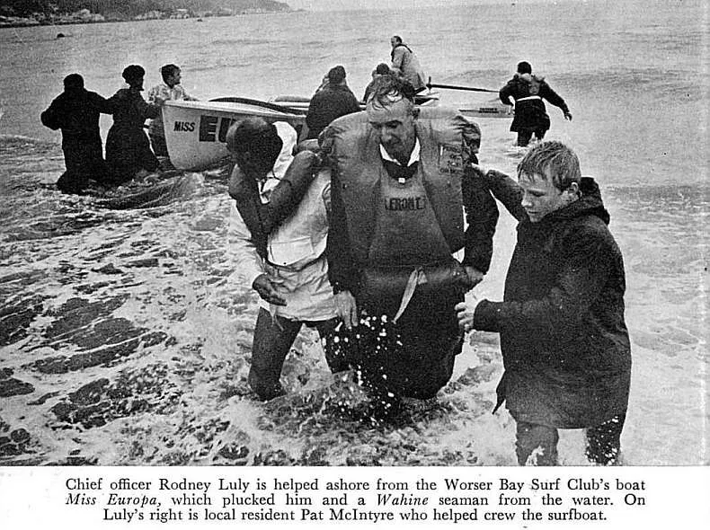 Chief officer Rodney Luly is helped ashore from the Worser Bay Surf Club's boat Miss Europa, which plucked him and a Wahine seaman from the water. On Luly's right is local resident Pat Mclntyre who helped crew the surtboat