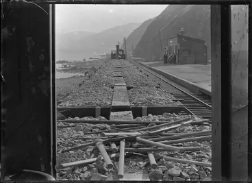 Image: Ngauranga Railway Station; view of the station, railway track, and a class D locomotive in middle distance, ca 1900, taken from a work-train van.