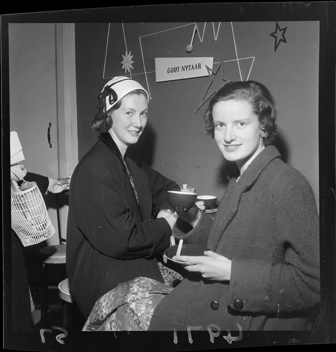 Coffee shop patrons having social cocktails, sign on wall says 'Happy New Year' in Danish