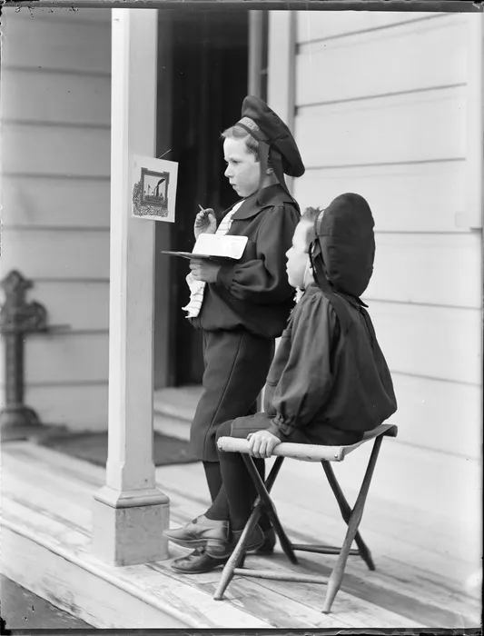 Edgar and Owen, on the porch of their house; Edgar is painting a picture hanging on the pillar, Royal Terrace, Kew, Dunedin